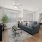 Spacious and well lit living room with wood flooring, large windows and open access to the kitchen