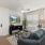 Spacious and well lit living room with wood flooring, large windows and open access to the kitchen