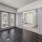 Spacious and well lit living room with wood flooring, large windows and open access to the kitchen
