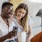 a man and woman sitting on a couch looking at a cell phone
